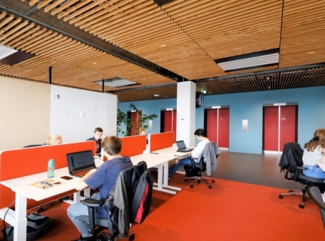 mensen zitten aan bureau met oranje vloer